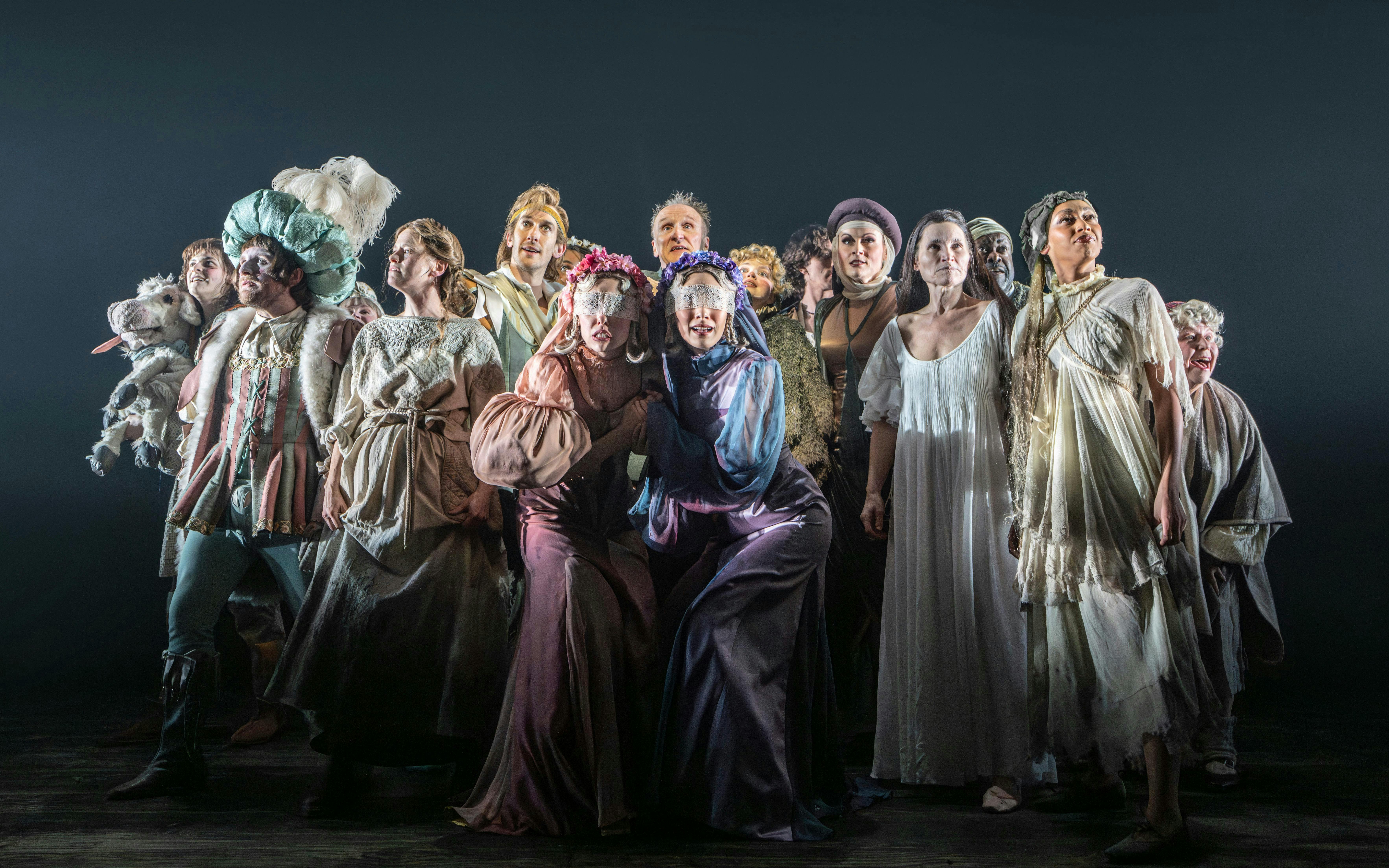 Cast of "Into The Woods" in costume on stage during a theatrical performance.