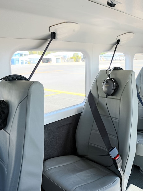 Interior seating of a small aircraft at Cairns Airport with headsets on seats.