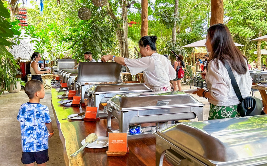 Tourists enjoying buffet during Chichen Itza sunrise tour in lush outdoor setting.
