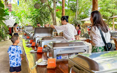 Tourists enjoying buffet during Chichen Itza sunrise tour in lush outdoor setting.