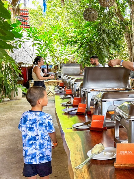 Tourists enjoying buffet during Chichen Itza sunrise tour in lush outdoor setting.