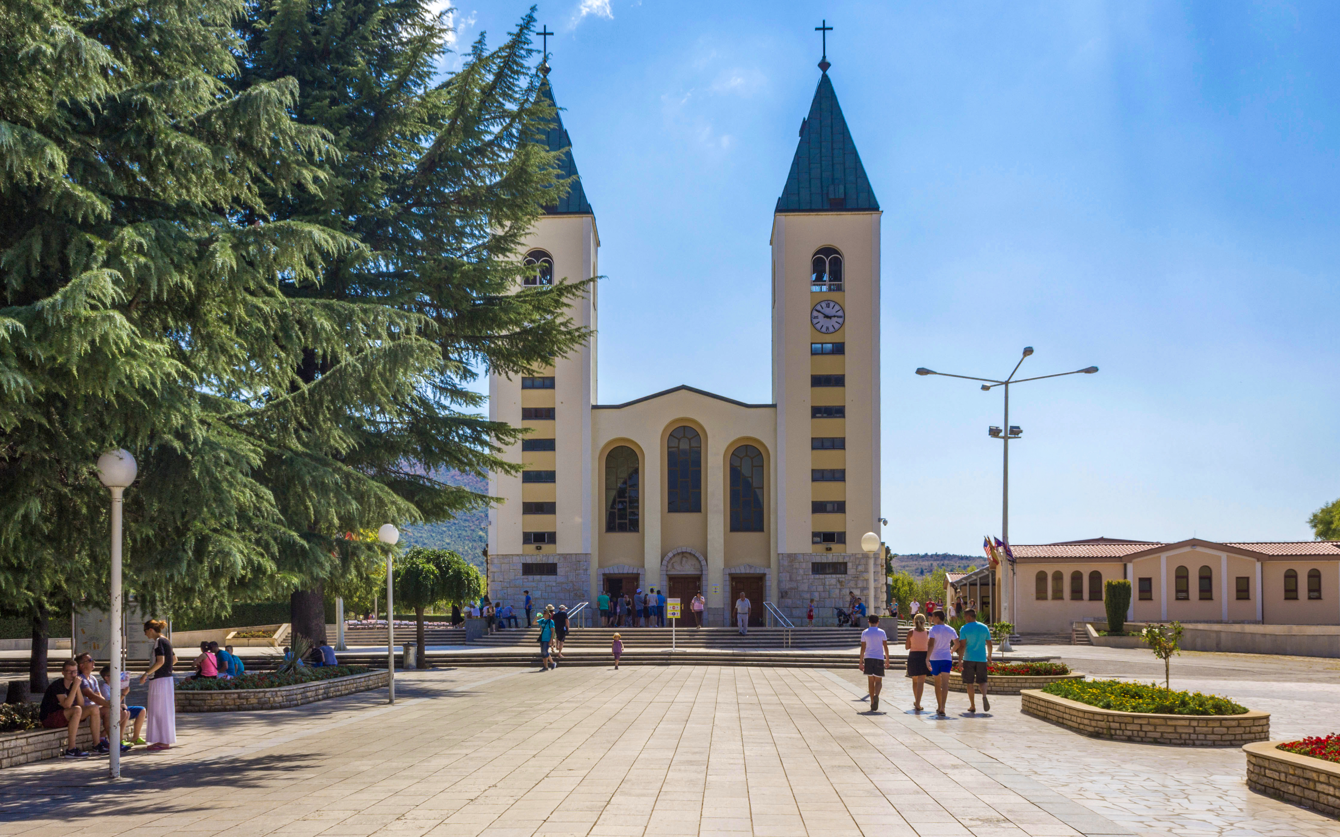 Frontal view of Saint James Church in Medjugorje with people in the square.