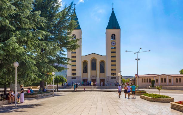 Frontal view of Saint James Church in Medjugorje with people in the square.