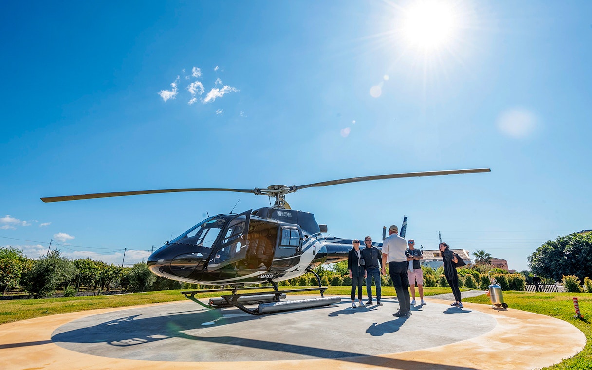 Helicopter on helipad with passengers preparing for Etna Volcano flight from Fiumefreddo.