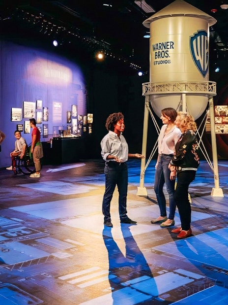 Guide leading tour at Warner Bros. Studio with visitors near iconic water tower.