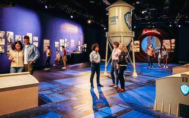Guide leading tour at Warner Bros. Studio with visitors near iconic water tower.