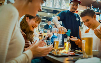 Group enjoying drinks and food at a local izakaya bar in Japan.