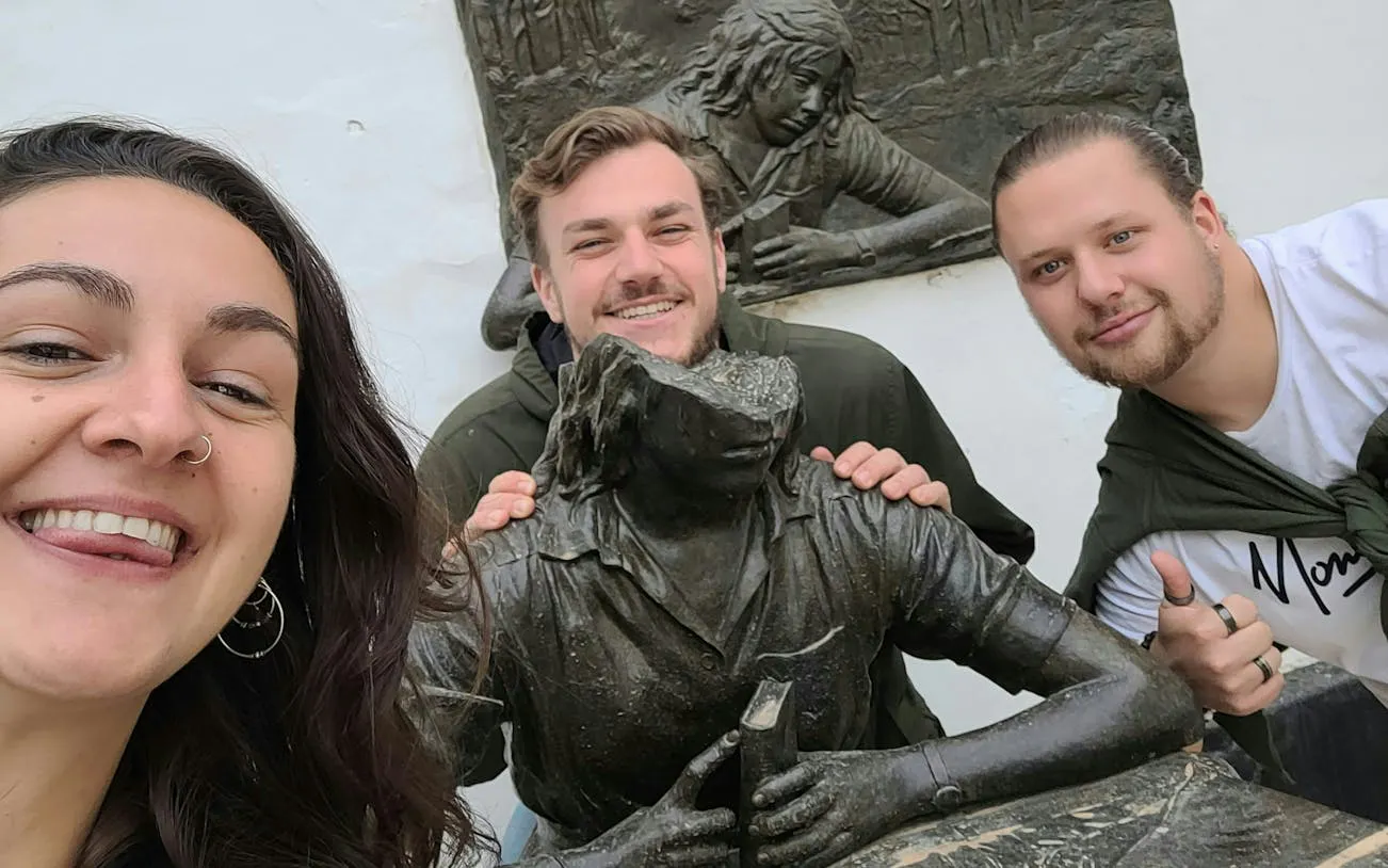 Visitors posing with a statue in Seville Old Town during a self-guided city exploration game.