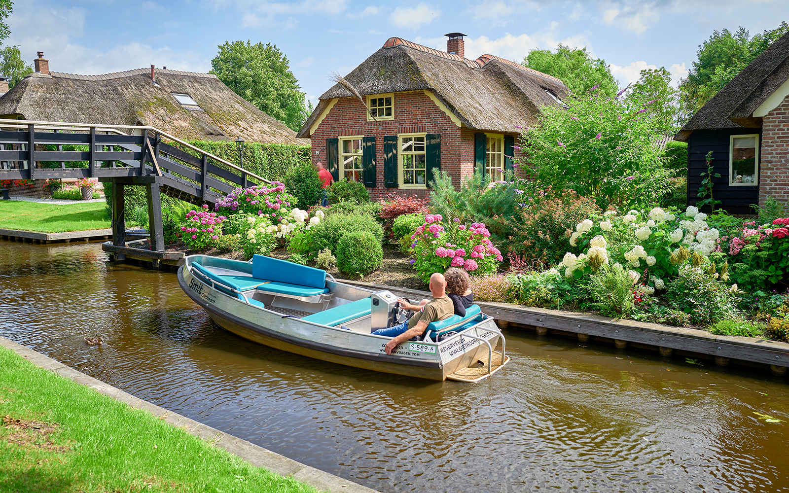 Private boat trip through Giethoorn canal with traditional thatched-roof houses.