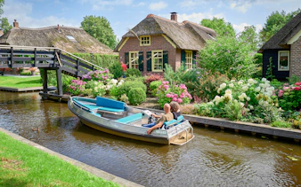 Private boat trip through Giethoorn canal with traditional thatched-roof houses.