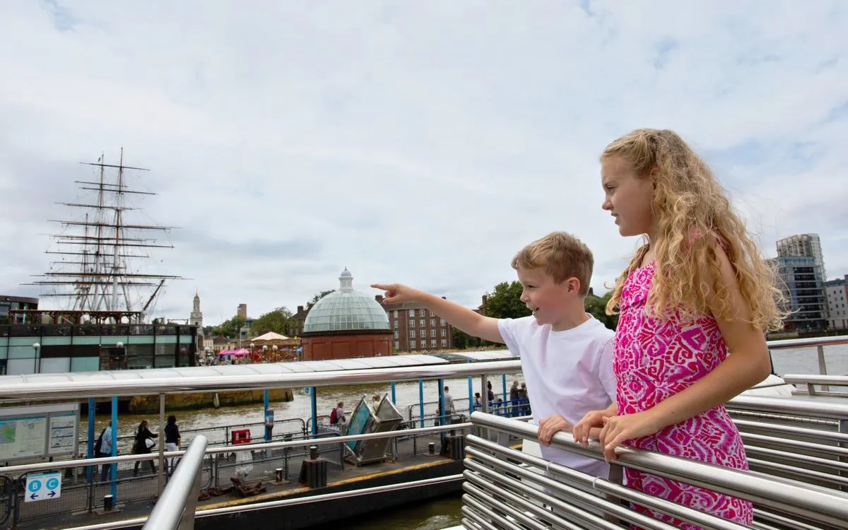 Children on a London HOHO cruise pointing at the Cutty Sark ship in Greenwich.