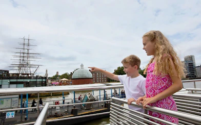 Children on a London HOHO cruise pointing at the Cutty Sark ship in Greenwich.