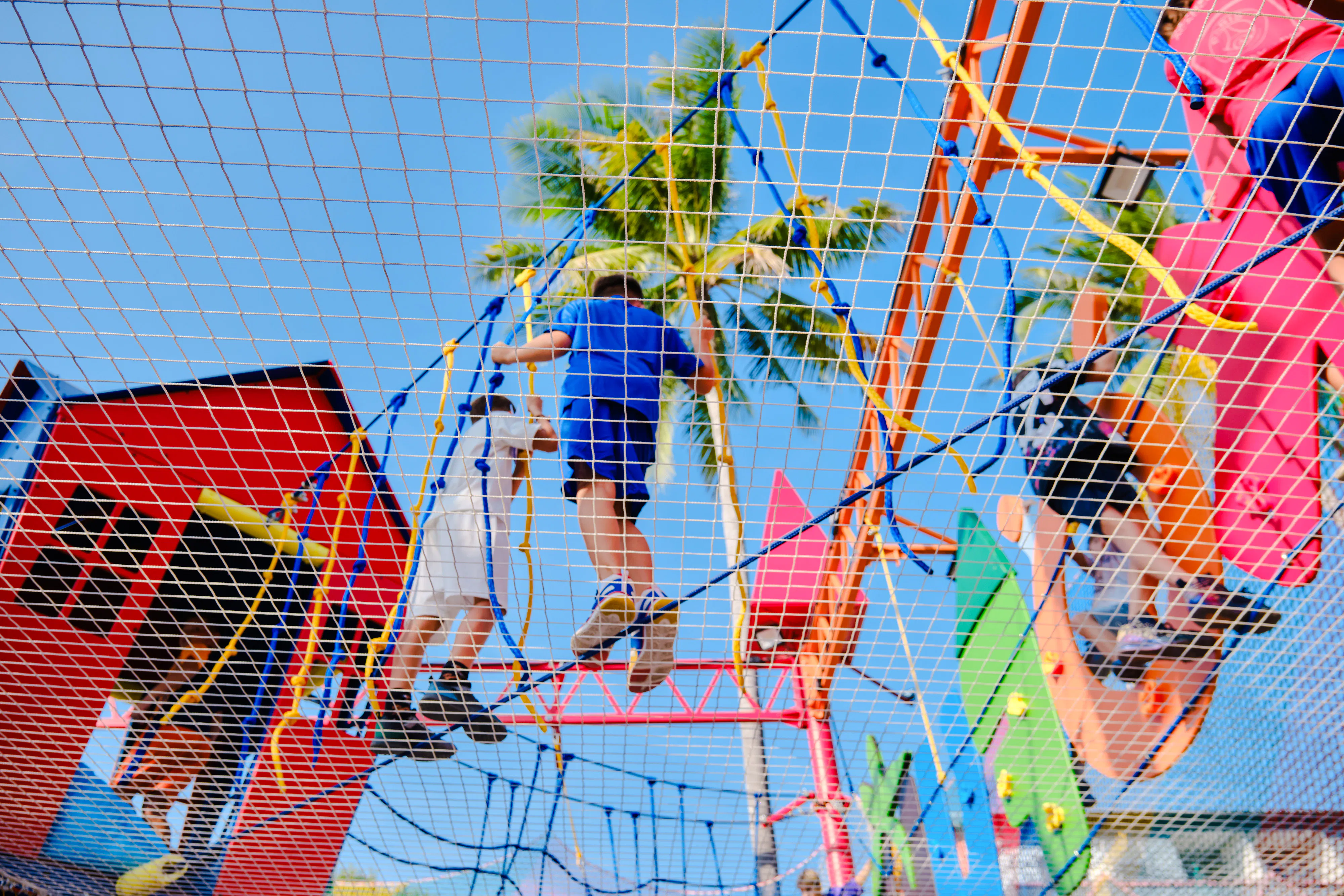 Children climbing a colorful ropes course at a birthday party in Phuket.
