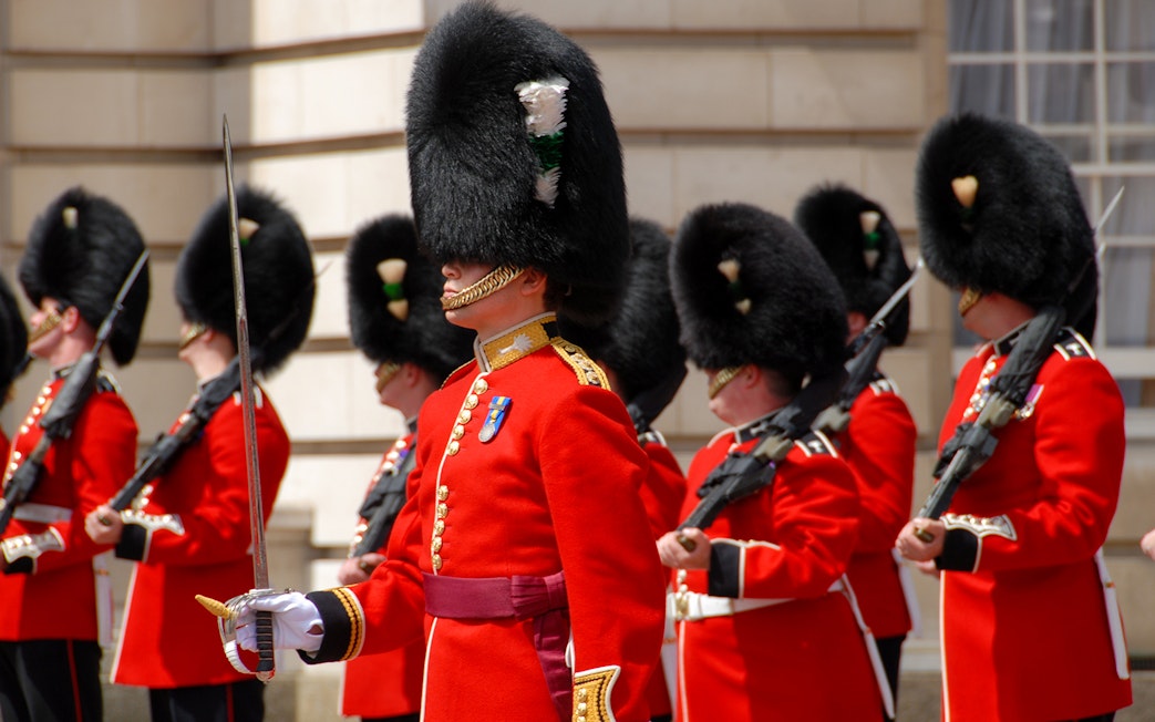 Guards in red uniforms and bearskin hats at Westminster during a walking tour.
