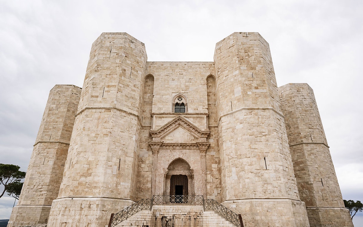 Castel del Monte's octagonal towers under a cloudy sky, Italy.