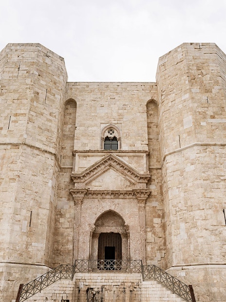 Castel del Monte's octagonal towers under a cloudy sky, Italy.