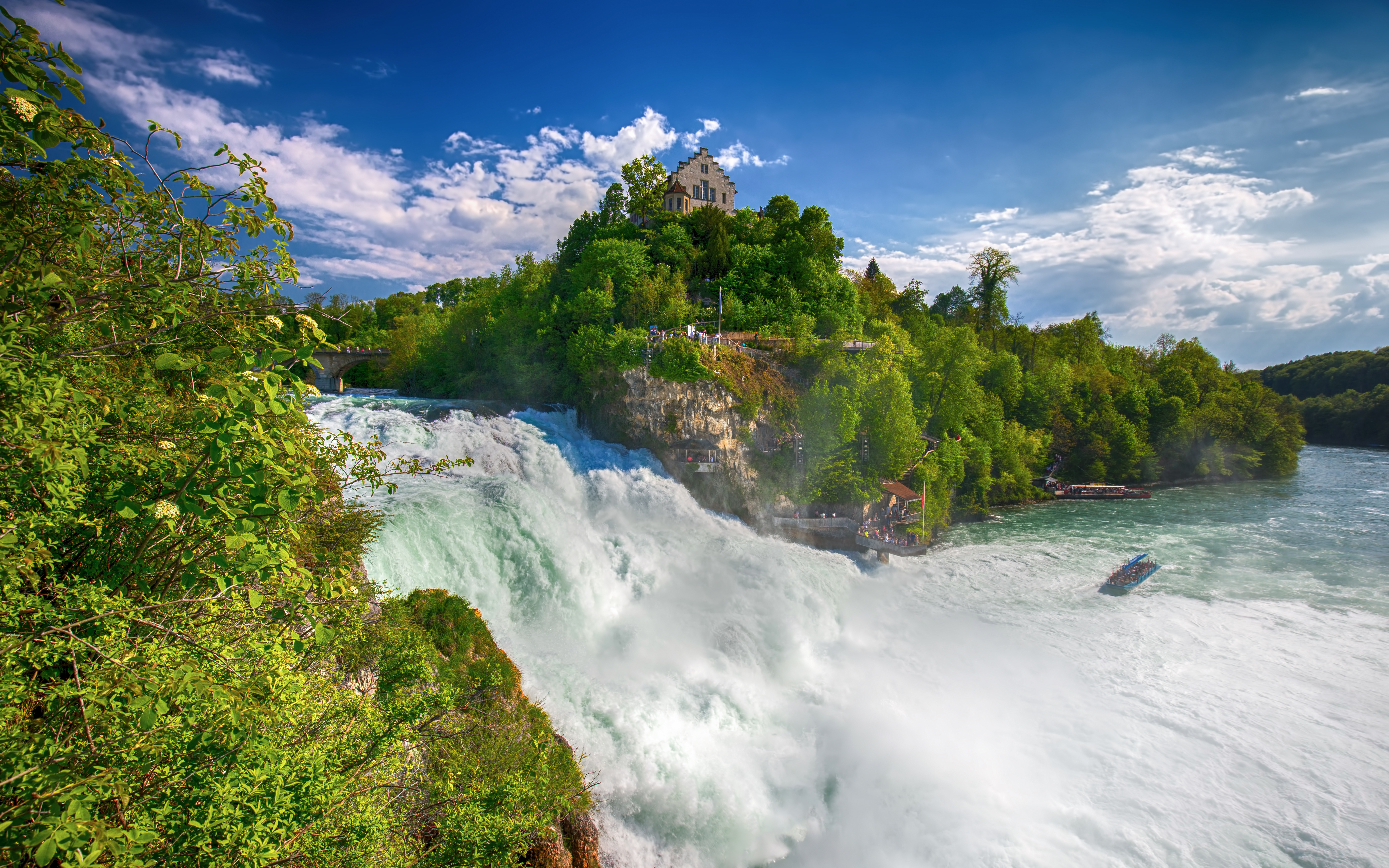 Rhine Falls with castle on hill and boat in river, Switzerland.