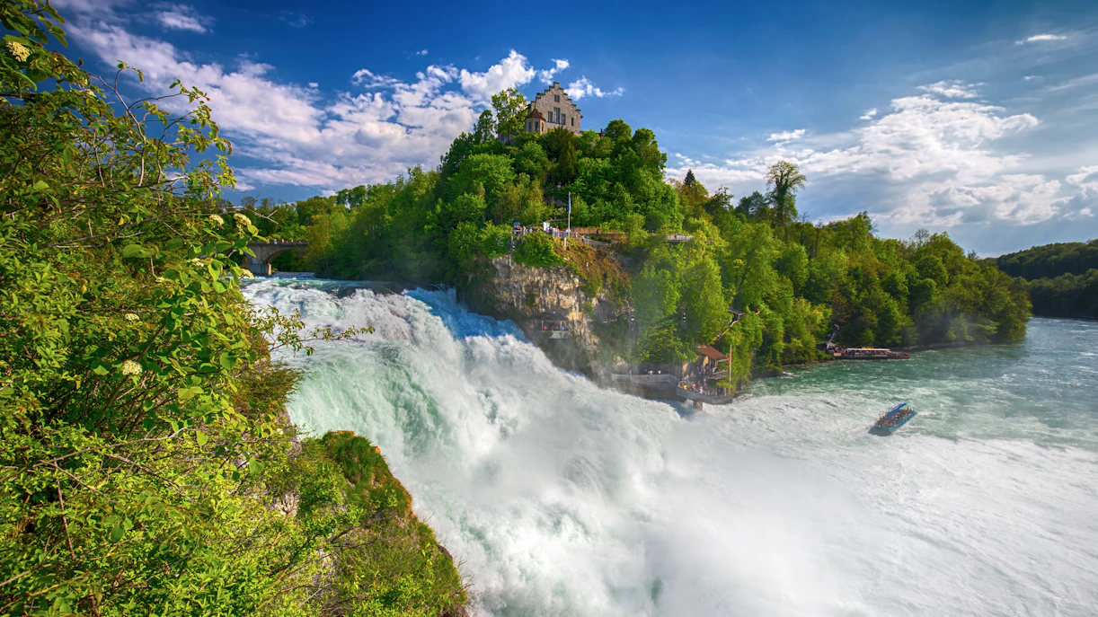 Rhine Falls with castle on hill and boat in river, Switzerland.