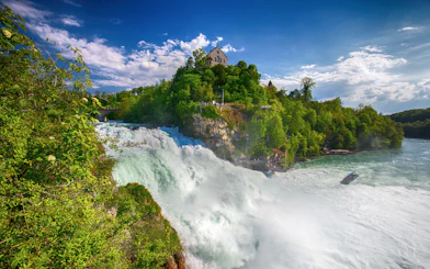 Rhine Falls with castle on hill and boat in river, Switzerland.