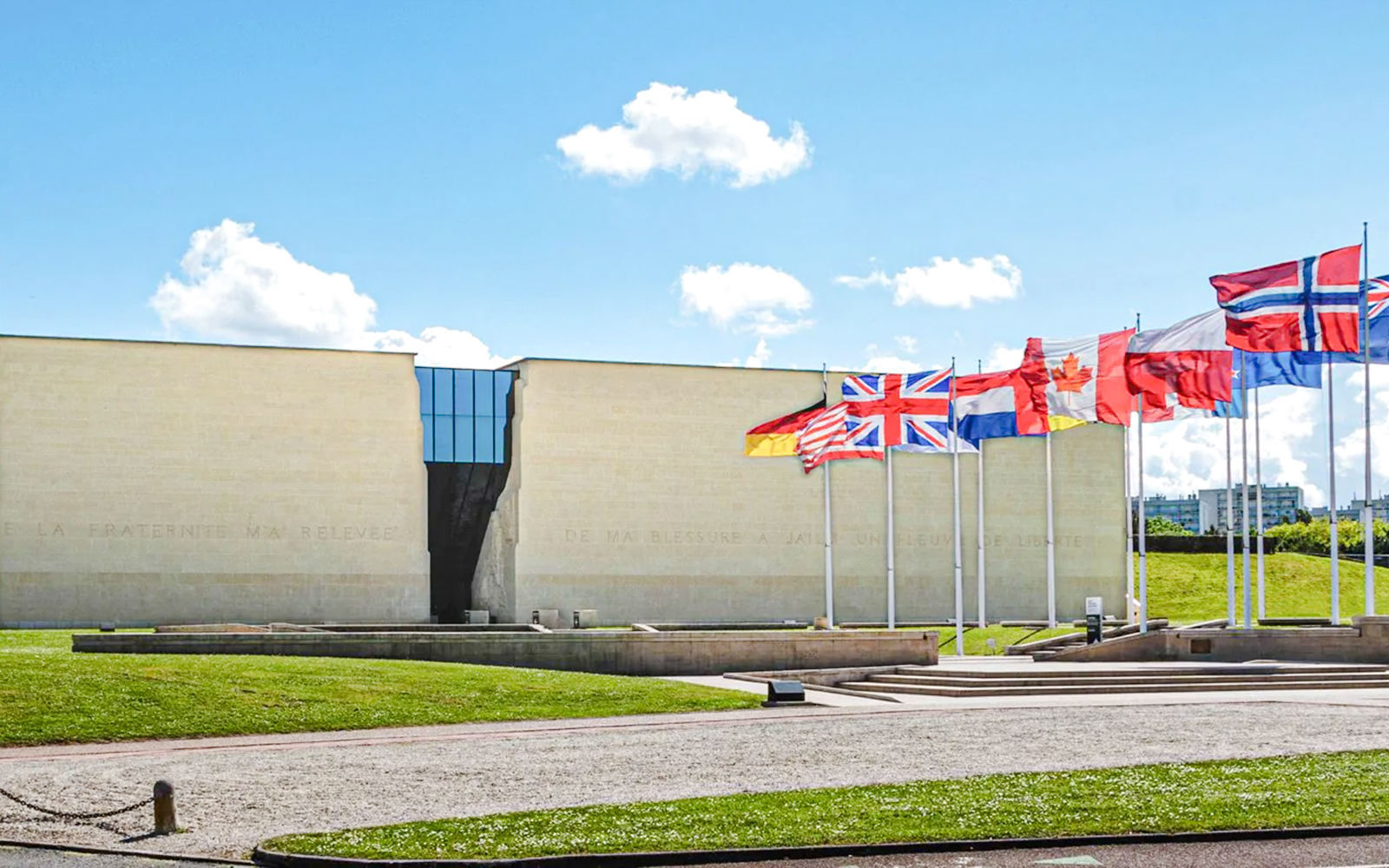 Exteriors of the Caen Memorial Museum with international flags displayed.