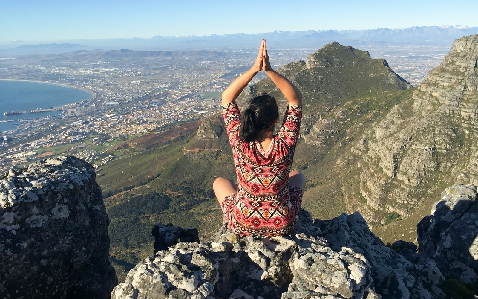 Person meditating on Table Mountain overlooking Cape Town.