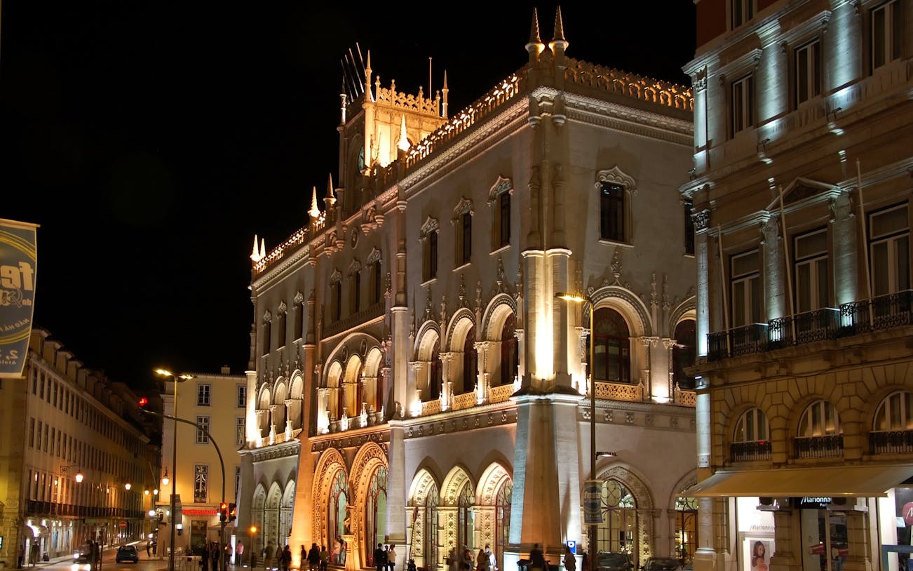 Rossio train station illuminated at night in Lisbon, Portugal.