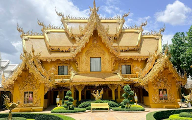 Golden temple facade with intricate carvings in Chiang Rai, part of Chiang Mai to Chiang Rai tour.