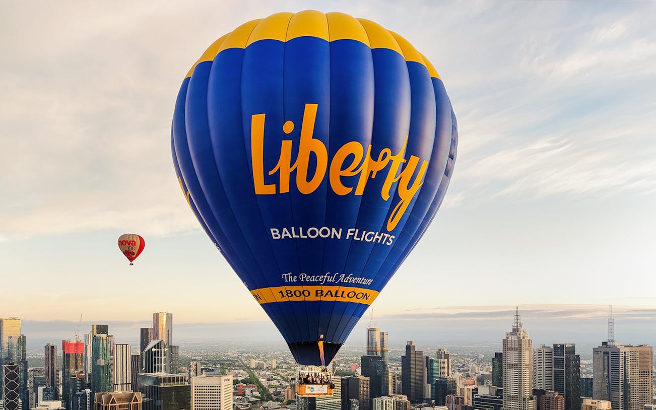 Hot air balloon over Melbourne skyline at sunrise.