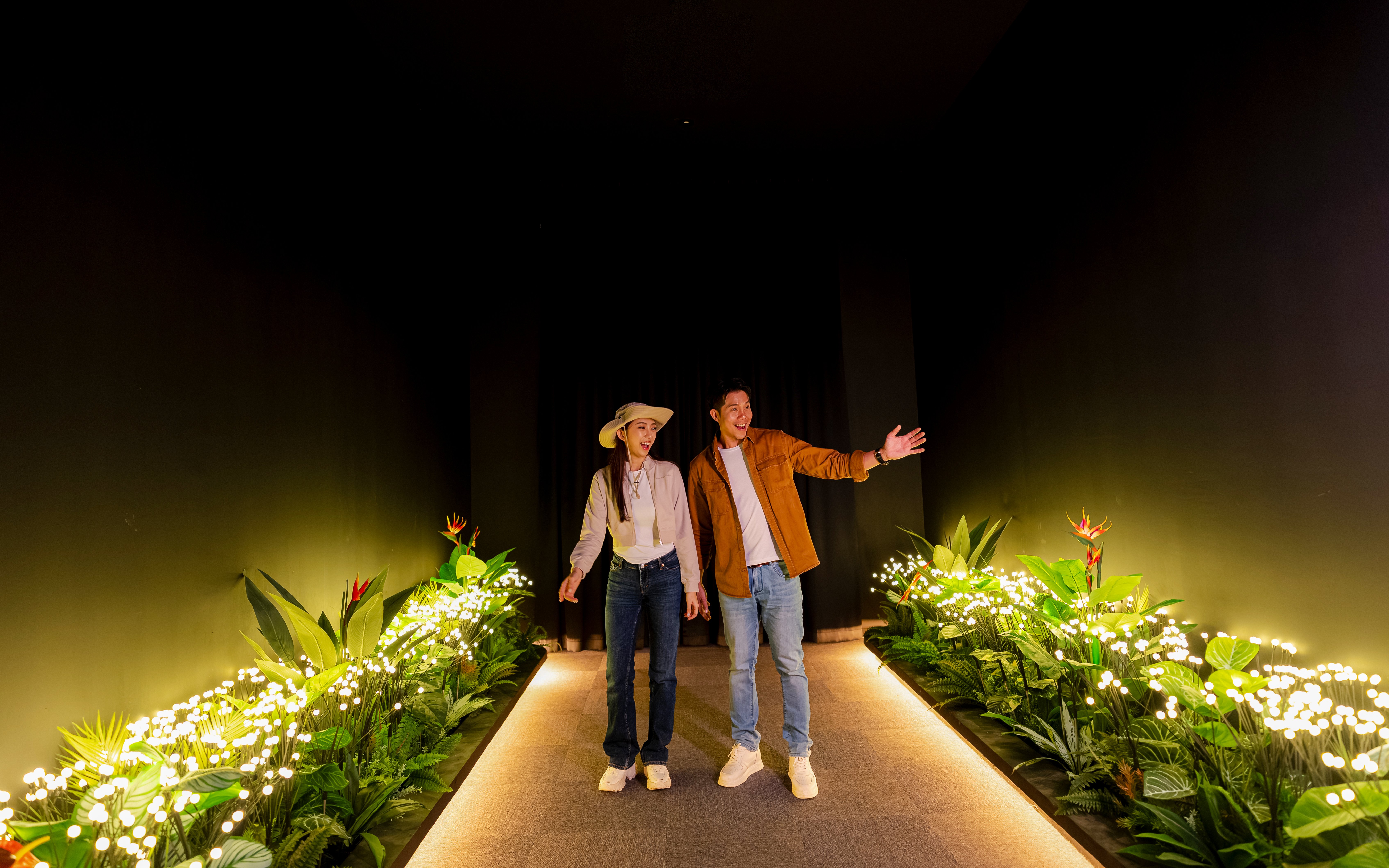 Couple exploring interactive nature elements at Enchanted Forest indoor experience.