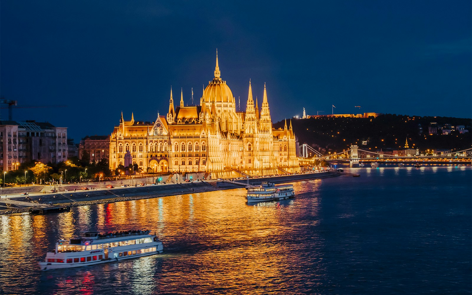 Nighttime cruise on the Danube River by the illuminated Hungarian Parliament in Budapest.