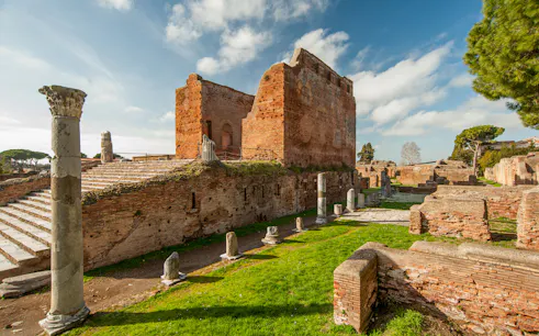 Ancient ruins and columns in Ostia Antica, Italy, under a clear sky.