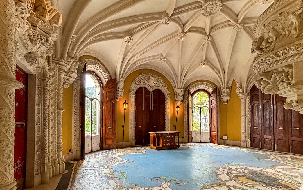 Interiors of Quinta da Regaleira with ornate ceiling and arched windows.