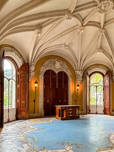 Interiors of Quinta da Regaleira with ornate ceiling and arched windows.