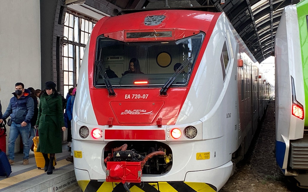Malpensa Express train at platform with passengers, connecting airport to Milan Central Station.