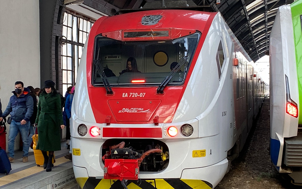 Malpensa Express train at platform with passengers, connecting airport to Milan Central Station.