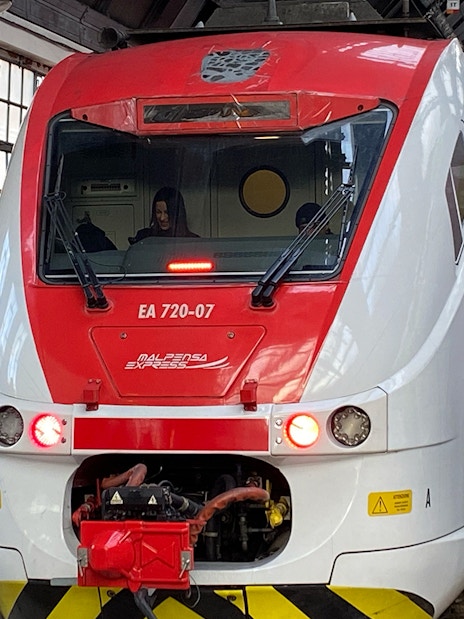 Malpensa Express train at platform with passengers, connecting airport to Milan Central Station.