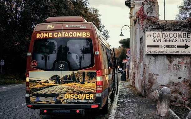 Tour bus parked near Catacombs of San Sebastiano entrance in Rome.