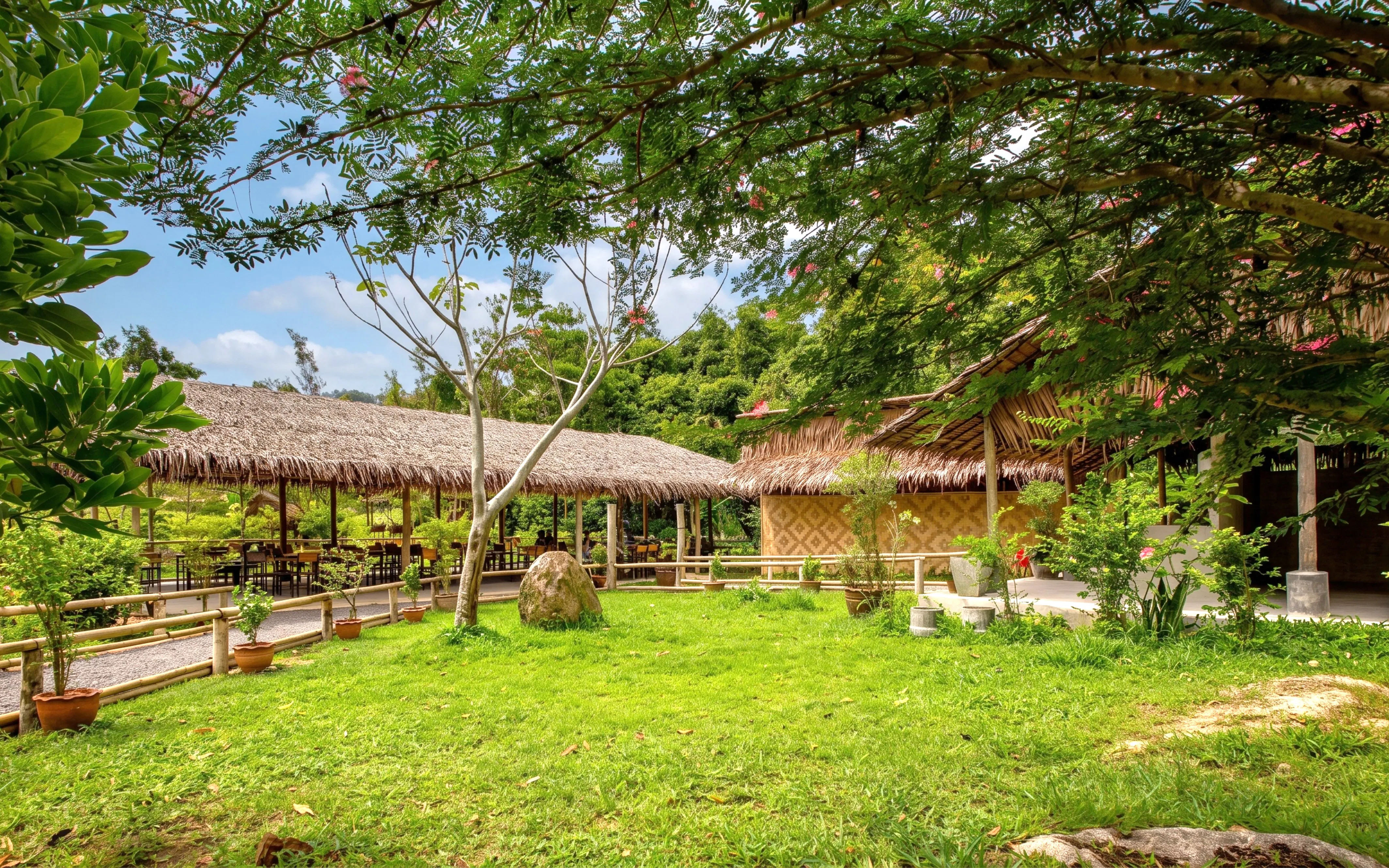 Thatched-roof huts in a lush garden at Phuket's Ethical Elephant Nature Park.