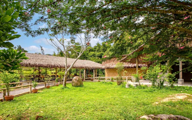 Thatched-roof huts in a lush garden at Phuket's Ethical Elephant Nature Park.
