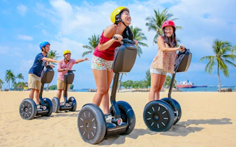Group enjoying Segway ride on sandy beach with palm trees, part of Gogreen Segway Eco Adventure.