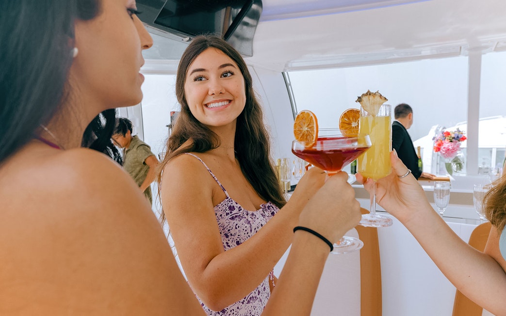 Women toasting with fruit garnished drinks on a boat.