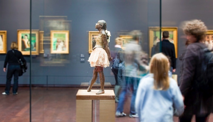 Orsay Museum interior with visitors viewing Impressionist paintings, Paris guided tour.