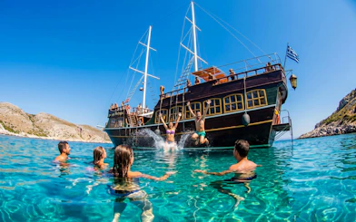 People swimming near a boat during a Rhodes sightseeing cruise.