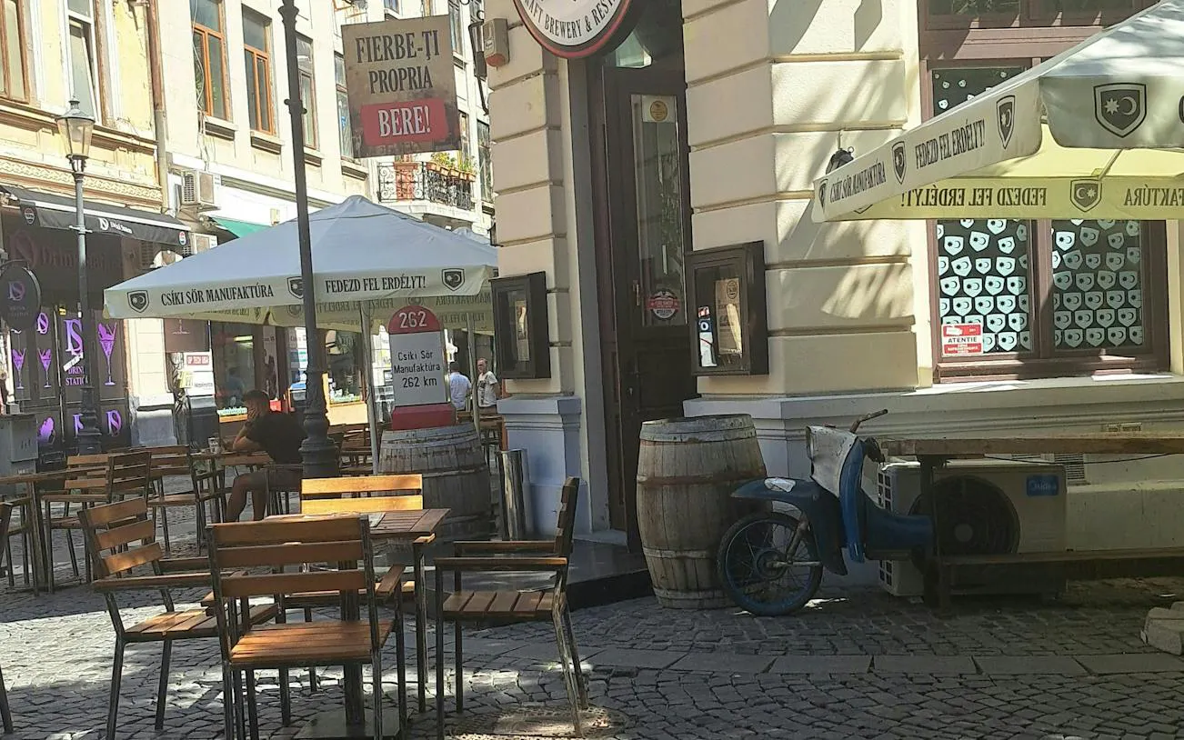 Outdoor café with wooden tables and chairs on a cobblestone street in Bucharest.
