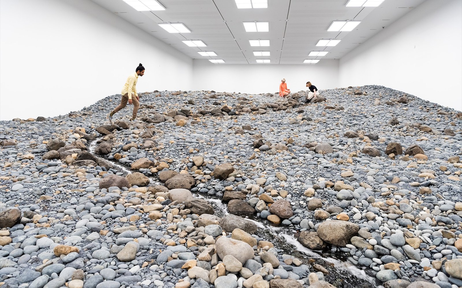 Visitors exploring Olafur Eliasson's rocky landscape installation at Gallery of Modern Art.