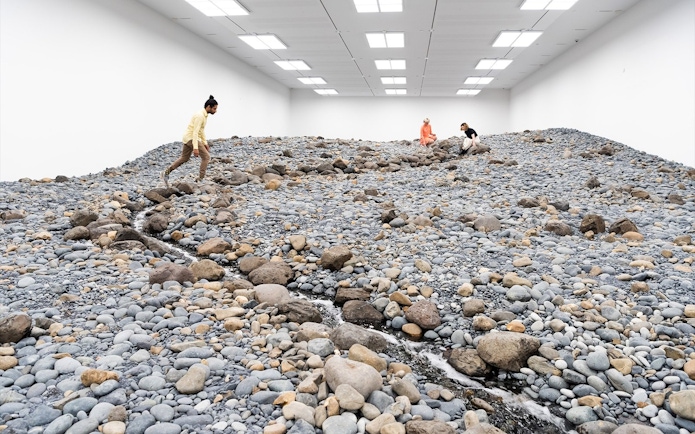 Visitors exploring Olafur Eliasson's rocky landscape installation at Gallery of Modern Art.