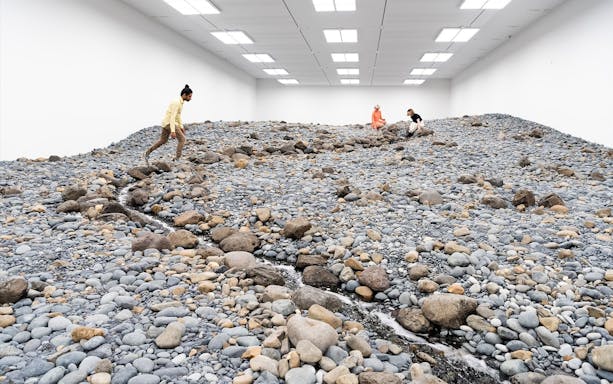 Visitors exploring Olafur Eliasson's rocky landscape installation at Gallery of Modern Art.