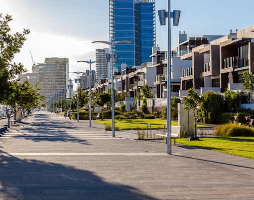 Docklands promenade in Melbourne with modern buildings and trees lining the walkway.