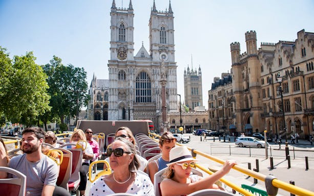 Open-top bus tour passing Westminster Abbey in London.