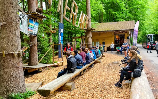 Visitors seated for a briefing at Ropes Park Interlaken, surrounded by lush forest.